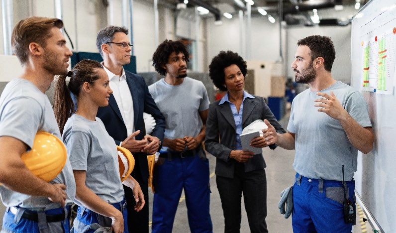 A group of people engaged in a discussion inside a factory.