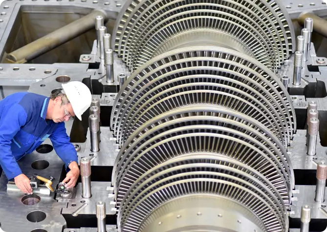 A skilled worker maintaining a massive turbine in a factory, ensuring its smooth operation.