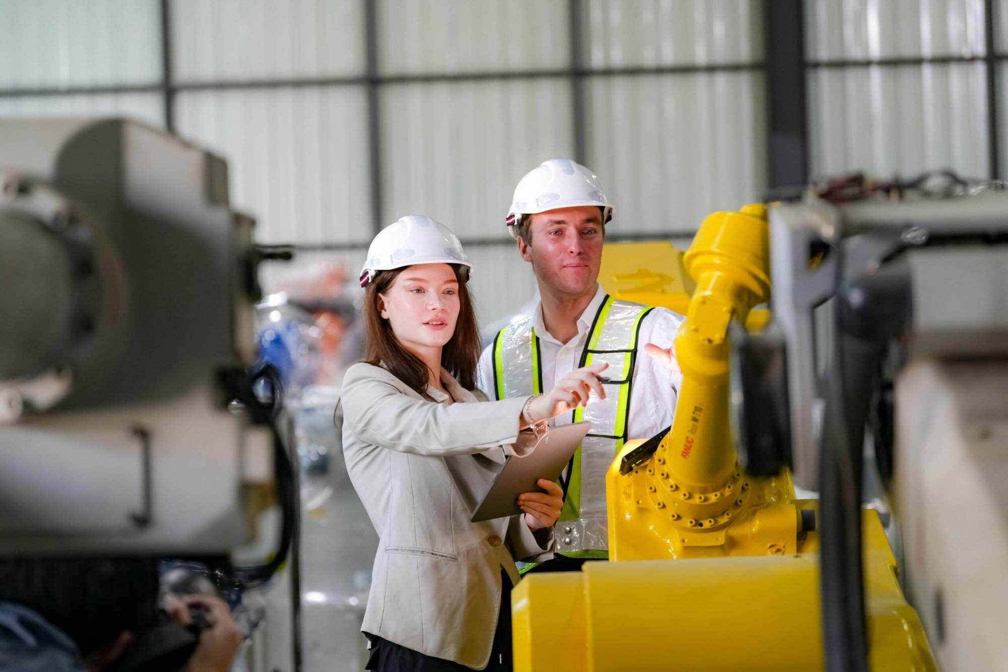 Engineers inspecting a yellow industrial robot in a factory setting.