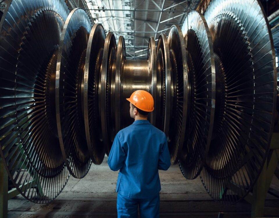 Engineer inspecting large industrial turbine in a factory setting