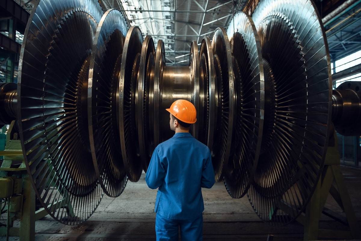 Engineer inspecting large industrial turbine in a factory setting